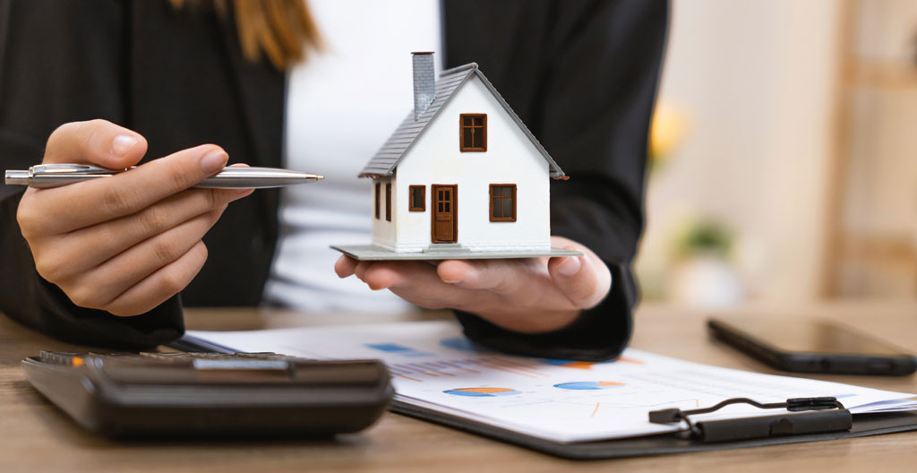 Mains tenant un stylo au-dessus d'une facture de charges, avec tasse de café et lunettes posées à côté sur un bureau